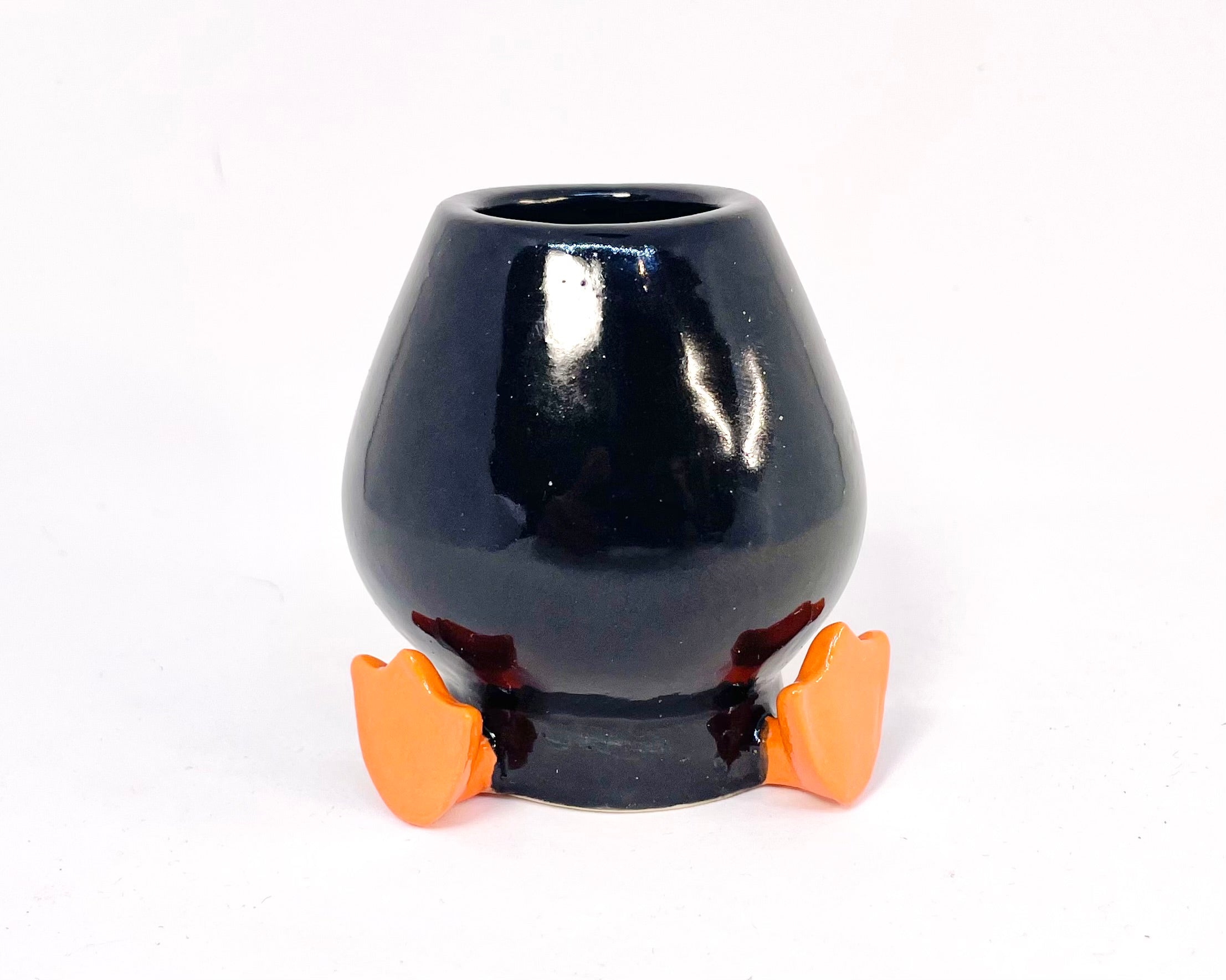 Black ceramic whisk holder with orange feet on a white background