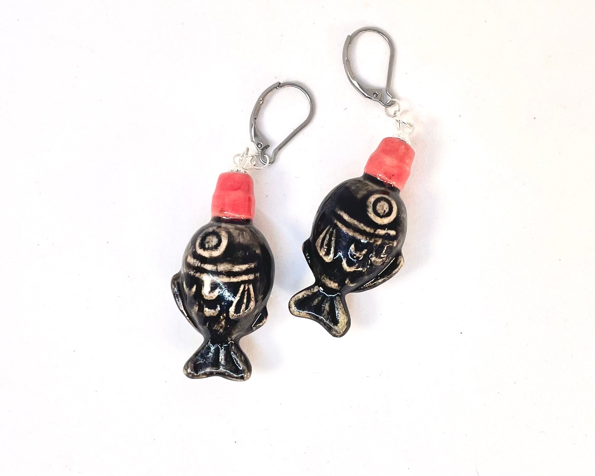 Black fish-shaped earrings with red accents on a white background