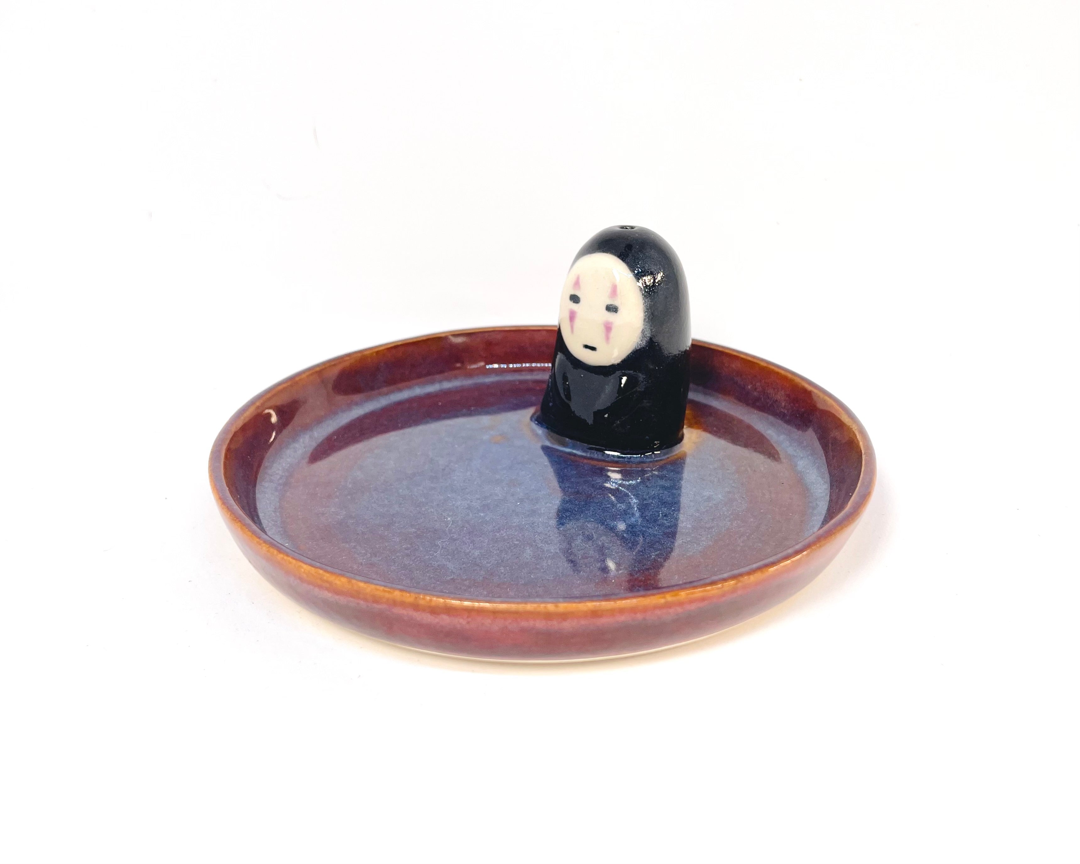 Relax with this charming handmade Noface incense holder and trinket dish. Perfect for holding jewelry or burning your favorite incense, this ceramic piece adds a touch of "kawaii" to your home.